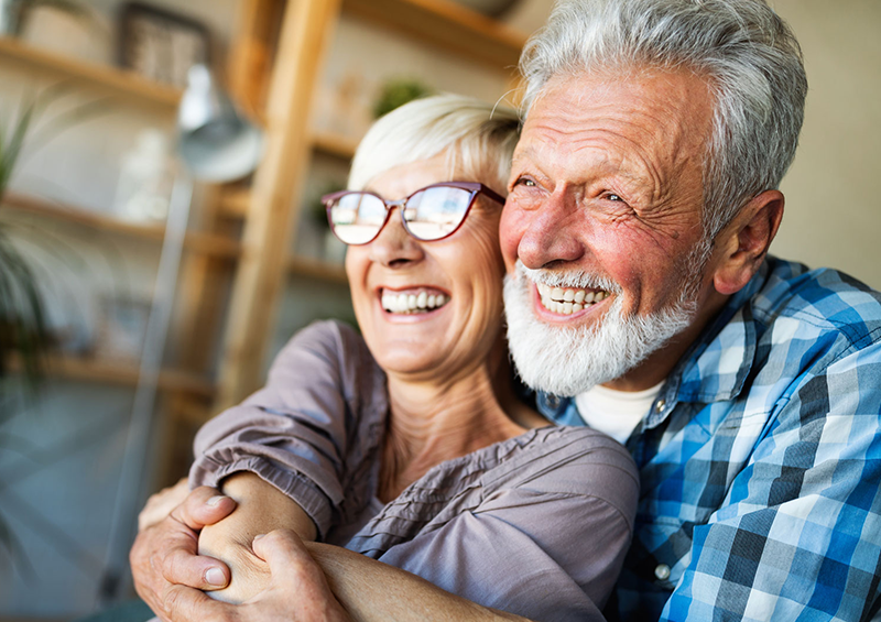 Coppia di signori anziani che sorridono abbracciandosi